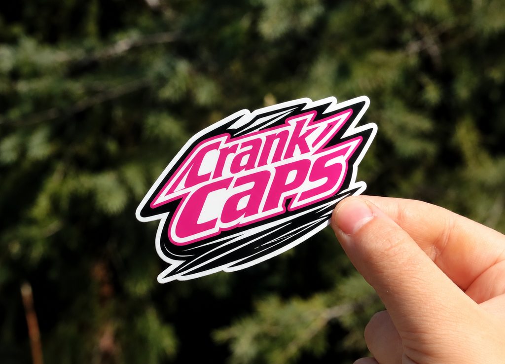 MTB Sticker by Crank Caps hand held against a blurred outdoor background
