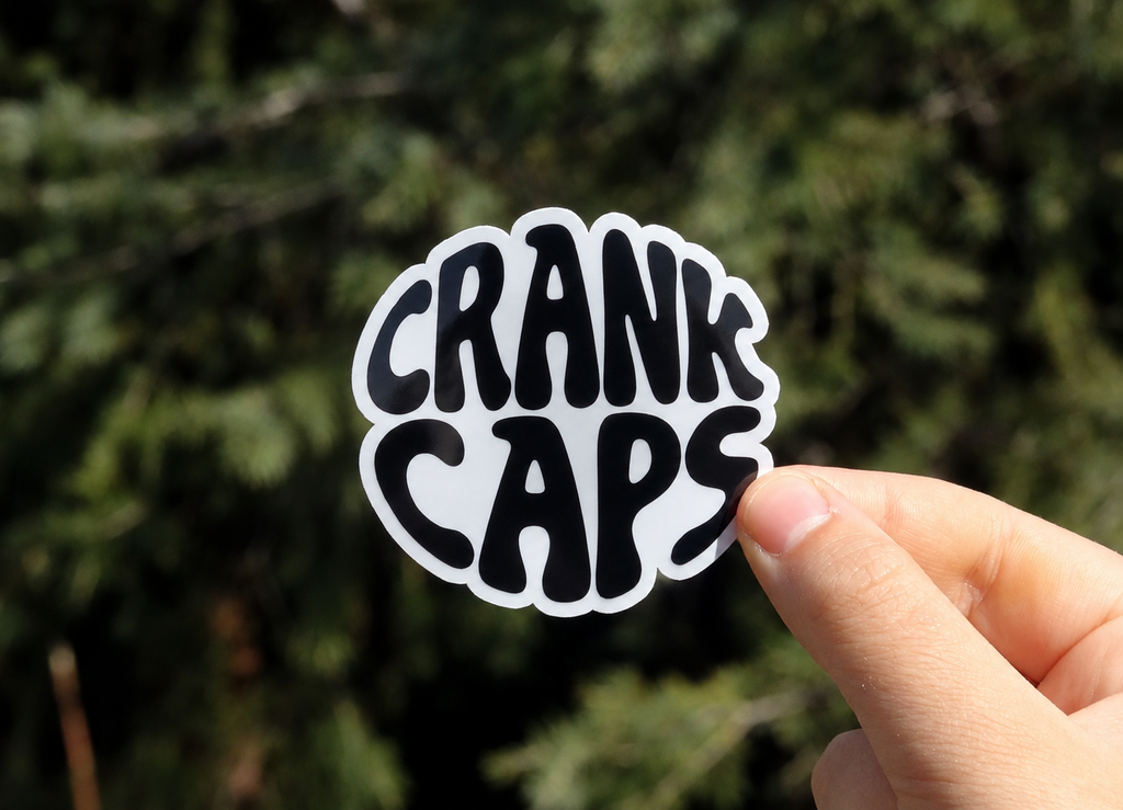 Groove MTB Sticker by CrankCaps on a blurred background on an outdoor setting. 