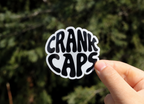 Groove MTB Sticker by CrankCaps on a blurred background on an outdoor setting. 